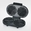 An open black waffle maker with heart-shaped waffle molds, photographed against a light gray and white background. Produktbild-Vorschau