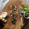 A sliced steak with sauce on a wooden board, with accompaniments. Voir les images du produit