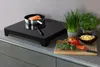 A kitchen counter with a portable induction cooktop, a pot with food, and fresh vegetables. Anteprima dell’immagine prodotto