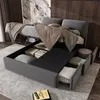 A modern bedroom with a grey upholstered bed frame featuring hydraulic lift storage and drawers. The bed is made, with blankets and pillows. Náhled obrázku produktu