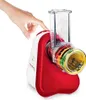 A hand is pressing a button on a red and white food processor with multiple attachments. Náhled obrázku produktu