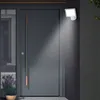 An LED outdoor light with a motion sensor is mounted on a textured wall next to a dark gray front door. Produktbild-Vorschau