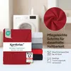 A stack of folded fitted sheets with a washing machine in the background. Produktbild-Vorschau