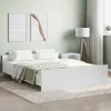 A white bed frame with white bedding and a beige throw blanket is set up in a bedroom with light green walls and two abstract paintings on the wall. Produktbild-Vorschau