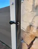 Close-up of a black bungee cord with a ball end attached to a metal pole, next to a transparent PVC sheet showing stacked logs. Produktbild-Vorschau