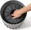 A hand is shown pressing into the center of a planter. Voir les images du produit