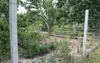 A wire fence in a garden with trees and plants behind it. Produktbild-Vorschau
