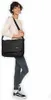 A woman is modeling a black messenger bag. Produktbild-Vorschau