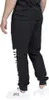 A person is wearing black sweatpants with white lettering on the side and white sneakers. Produktbild-Vorschau