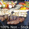 A variety of food items, including steaks, chicken, and skewers with vegetables, are being grilled on a black grill mat. Produktbild-Vorschau