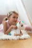 A young girl is lying on a fluffy rug, holding a plush unicorn toy. Podgląd zdjęcia produktu