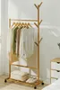 A wooden garment rack with clothes hanging on it, placed in a room next to a nightstand. Produktbild-Vorschau