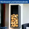 A black metal firewood rack filled with logs, mounted on a wall next to a window and a chair. Produktbild-Vorschau