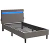 A twin-size bed frame with a grey upholstered headboard featuring blue LED lighting, set against a white background. Náhled obrázku produktu