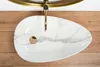 A top-down view of a white marble-patterned sink with a gold faucet and drain, set against a wooden background. Náhled obrázku produktu