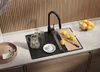 A kitchen sink area with a black sink, faucet, pitcher of water with mint, lemons, a cutting board, and a bowl of fruit. Produktbild-Vorschau