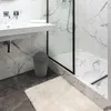 A modern bathroom with a sink, shower, and a trash can. Náhľad obrázku produktu