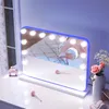 A vanity mirror with lights on a white dresser, next to a window with lace curtains. Náhled obrázku produktu