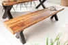 A wooden bench with black X-shaped legs is shown in a room with a white floor. Produktbild-Vorschau