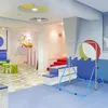 A brightly colored indoor play area for children, featuring a gymnastics bar, a scooter, and seating. Voir les images du produit
