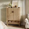 A wooden shoe cabinet with shoes on the bottom shelf, placed in a room with a chair and curtains. Podgląd zdjęcia produktu