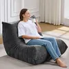 A woman sits on a large, dark gray beanbag chair, holding a mug and saucer. Produktbild-Vorschau