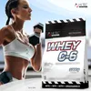 A woman is lifting weights next to a bag of protein powder. Produktbild-Vorschau