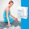 A woman in a blue towel sitting by a hot tub with a product box next to her. Produktbild-Vorschau