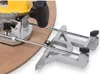 A close-up shot of a router with a circle cutting jig attached, resting on a piece of particle board. Náhled obrázku produktu