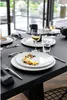 A formal dining table setting with plates, cutlery, and glasses. Produktbild-Vorschau