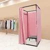 A pink changing room with clothes on a rack in the background. Voir les images du produit