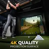 A man is playing golf on a simulator with a large screen displaying a golf course. Produktbild-Vorschau