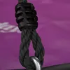 A close-up of a black rope with a silver ring attached, against a purple background. Voir les images du produit