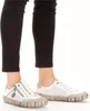 A close-up shot of a person's feet wearing white sneakers and black pants. Podgląd zdjęcia produktu