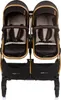 A front view of a black and gold double stroller against a white background. Produktbild-Vorschau