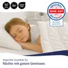 A young child sleeping peacefully under a white duvet on a bed. Produktbild-Vorschau