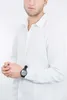 A man wearing a white shirt and a black digital watch. Voir les images du produit