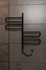 A black towel dryer mounted on a tiled wall. Náhľad obrázku produktu