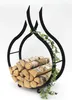 A black metal firewood rack shaped like flames, filled with logs and decorated with a green ivy vine, against a white background. Produktbild-Vorschau