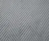 A close-up view of a gray quilted blanket with a chevron pattern. Podgląd zdjęcia produktu