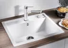 A white kitchen sink with a chrome and white faucet, set on a wooden countertop. A waffle maker and waffles are visible in the background. Produktbild-Vorschau