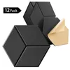 A group of black hexagonal acoustic panels, with one panel peeling back to reveal adhesive backing. Produktbild-Vorschau