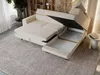 A sectional sofa with its storage compartments open, displayed in a living room setting. Produktbild-Vorschau