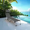 A lounge chair is placed on a patio next to an infinity pool with the ocean and palm trees in the background. Náhled obrázku produktu