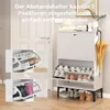 A white shoe cabinet with two flip-down drawers, displaying shoes and boots, placed in a hallway next to a door. An umbrella is hanging on the side. Produktbild-Vorschau