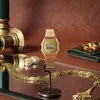 A golden Casio watch is displayed on a stand, surrounded by other golden accessories like a necklace and earrings, on a reflective surface with a brown background. Náhľad obrázku produktu