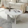 A round coffee table with a marble-like finish is placed on a rug in a living room setting, next to a couch. Voir les images du produit