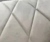 A close-up view of a beige upholstered fabric with a diamond-shaped quilting pattern. Anteprima dell’immagine prodotto