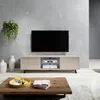 A modern living room scene featuring a TV lowboard with a television on top, a coffee table with decorative items, and a hanging plant. Produktbild-Vorschau