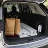 The inside of a car trunk with shopping bags and folded tables. Produktbild-Vorschau